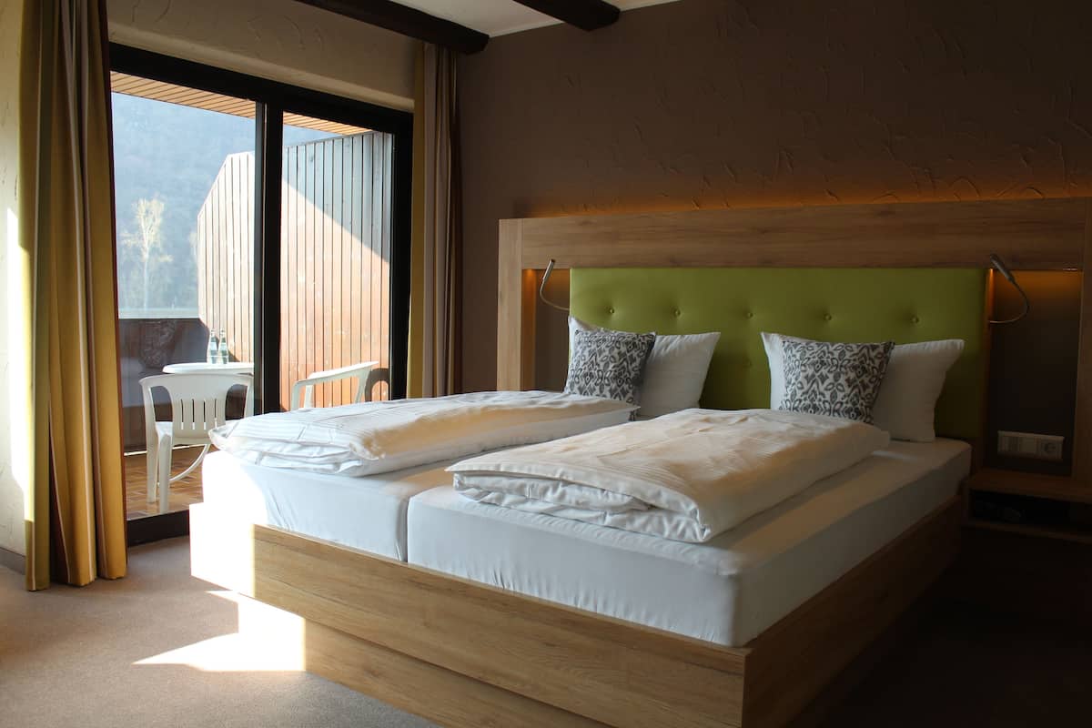 A double bed with two pillows, a wooden headboard, and a nightstand.