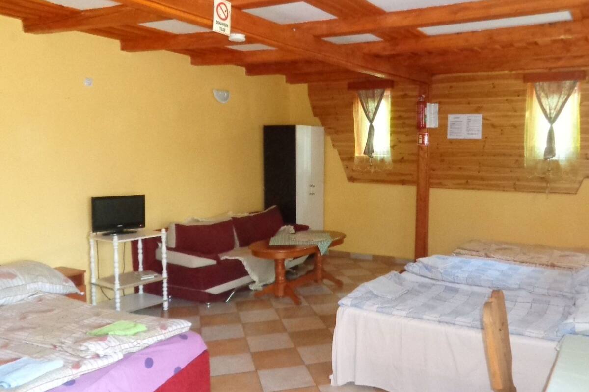 A cozy room with a checkered floor, a sofa, a small table, a television, and a bed.
