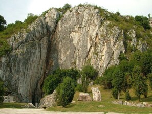 A large rock formation with a small building at its base.