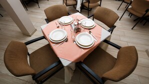 Un espace repas avec des tables dressées pour quatre personnes, chacune agrémentée d’assiettes blanches, de couverts et de verres.