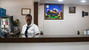 Un comptoir d’accueil avec un certificat encadré accroché au mur, une horloge et un tableau.