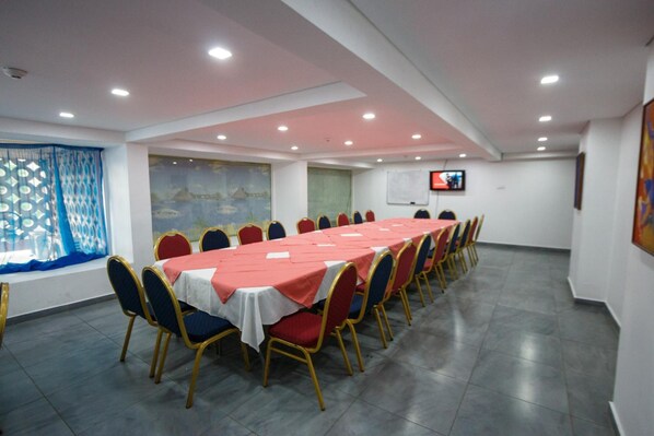 A conference room with a long table, chairs, and a TV screen on the wall.