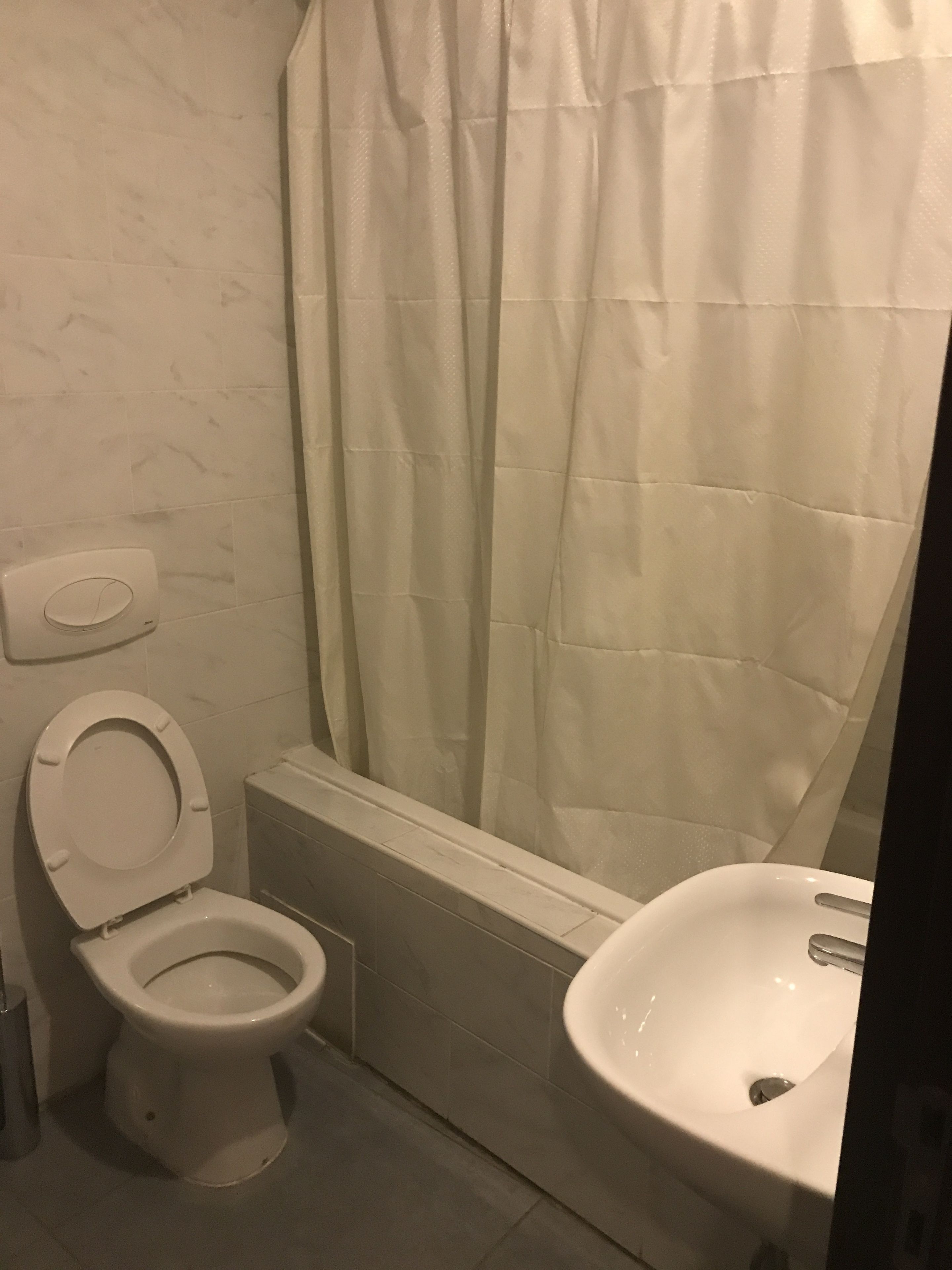 Un baño con inodoro, cortina de ducha y lavamanos.