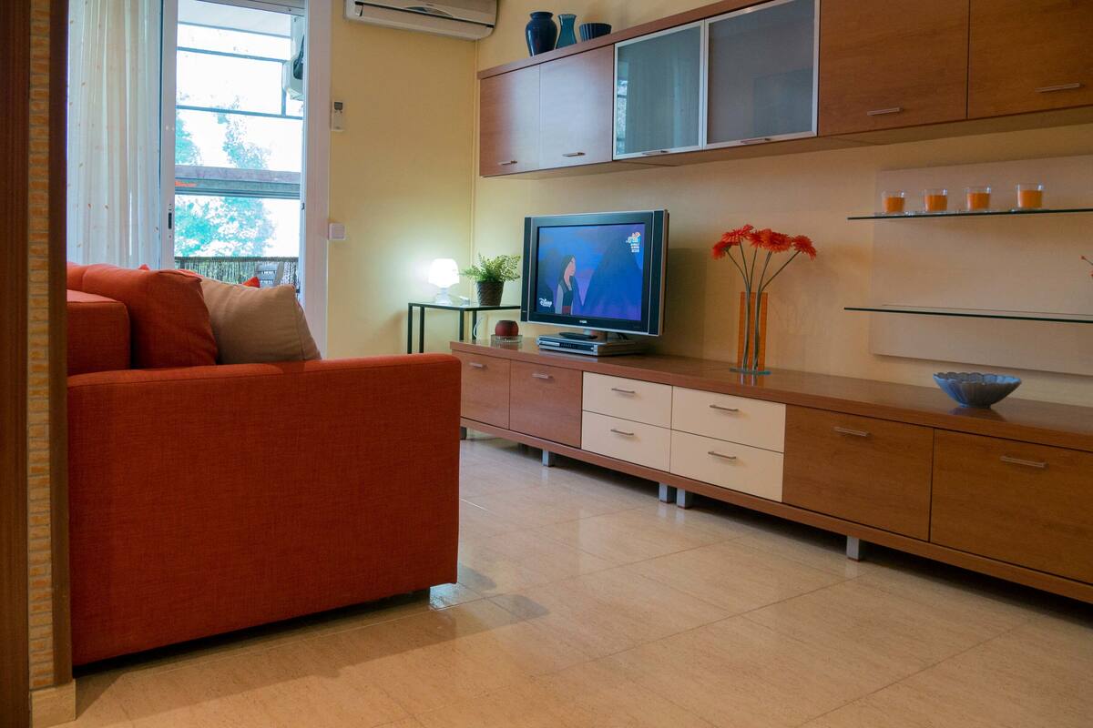 Ein modernes Wohnzimmer mit einem roten Sofa, einem Fernseher und einer Vitrine.