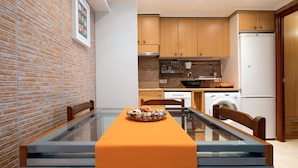 A modern kitchen with wooden cabinets, a built-in oven, and a washing machine. - Apartamento Els Cards (Sant Pere de Ribes)