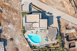 An aerial view of a property with a swimming pool, multiple buildings, and a large open area.