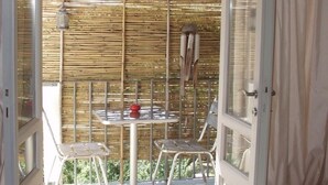Une chambre avec un lit, une table et des chaises, une fenêtre et un balcon avec un mur en bambou.