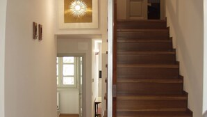 Un escalier en bois menant à un niveau supérieur, avec un luminaire fixé au plafond.