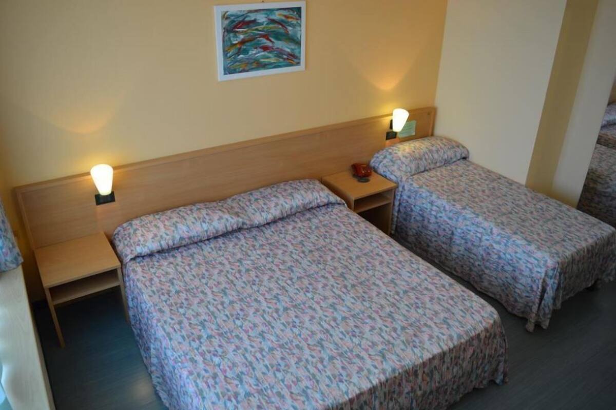 Ein Zimmer mit zwei Einzelbetten, jeweils mit Nachttisch und Lampe.