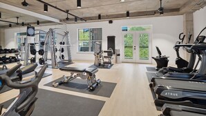 A modern gym with various exercise equipment, large windows, and a clean, spacious layout. - Kasa Downtown Austin (Austin)