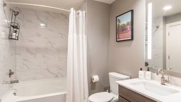 A modern bathroom with a bathtub, toilet, and vanity.
