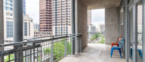 A balcony with a concrete floor, metal railing, and two blue chairs.