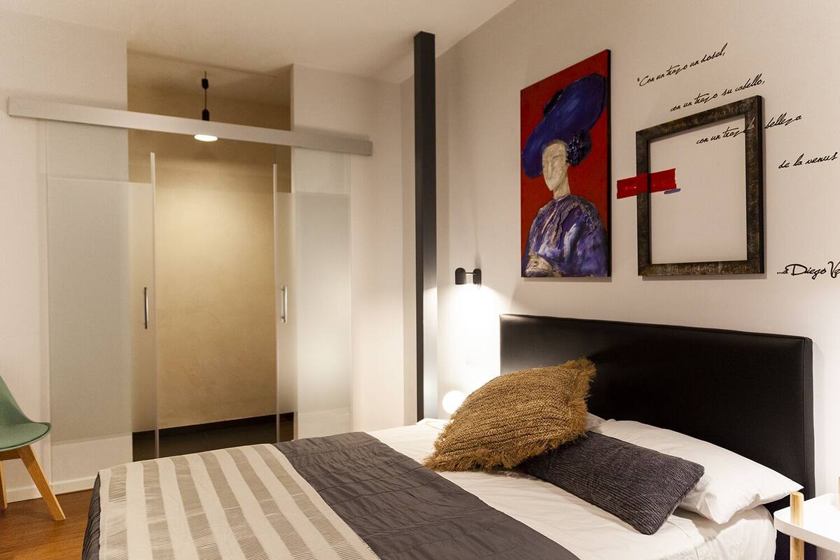 Un dormitorio moderno con cama, armario y obras de arte en la pared.