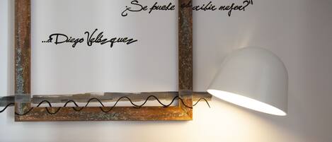 A framed quote on a wall with a lamp and a chair below.