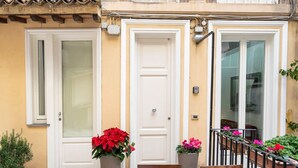 A building facade with three white doors, a tiled entrance, and potted plants. - White Style Alcove - Piazza Di Spagna (Roma)
