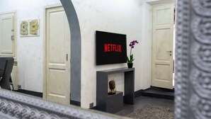A modern interior with a flat-screen TV mounted on a wall, a small fireplace, and a door with a decorative handle. - White Style Alcove - Piazza Di Spagna (Roma)