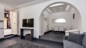 A modern living room with a grey sofa, a flat-screen TV, and a grey rug. - White Style Alcove - Piazza Di Spagna (Roma)