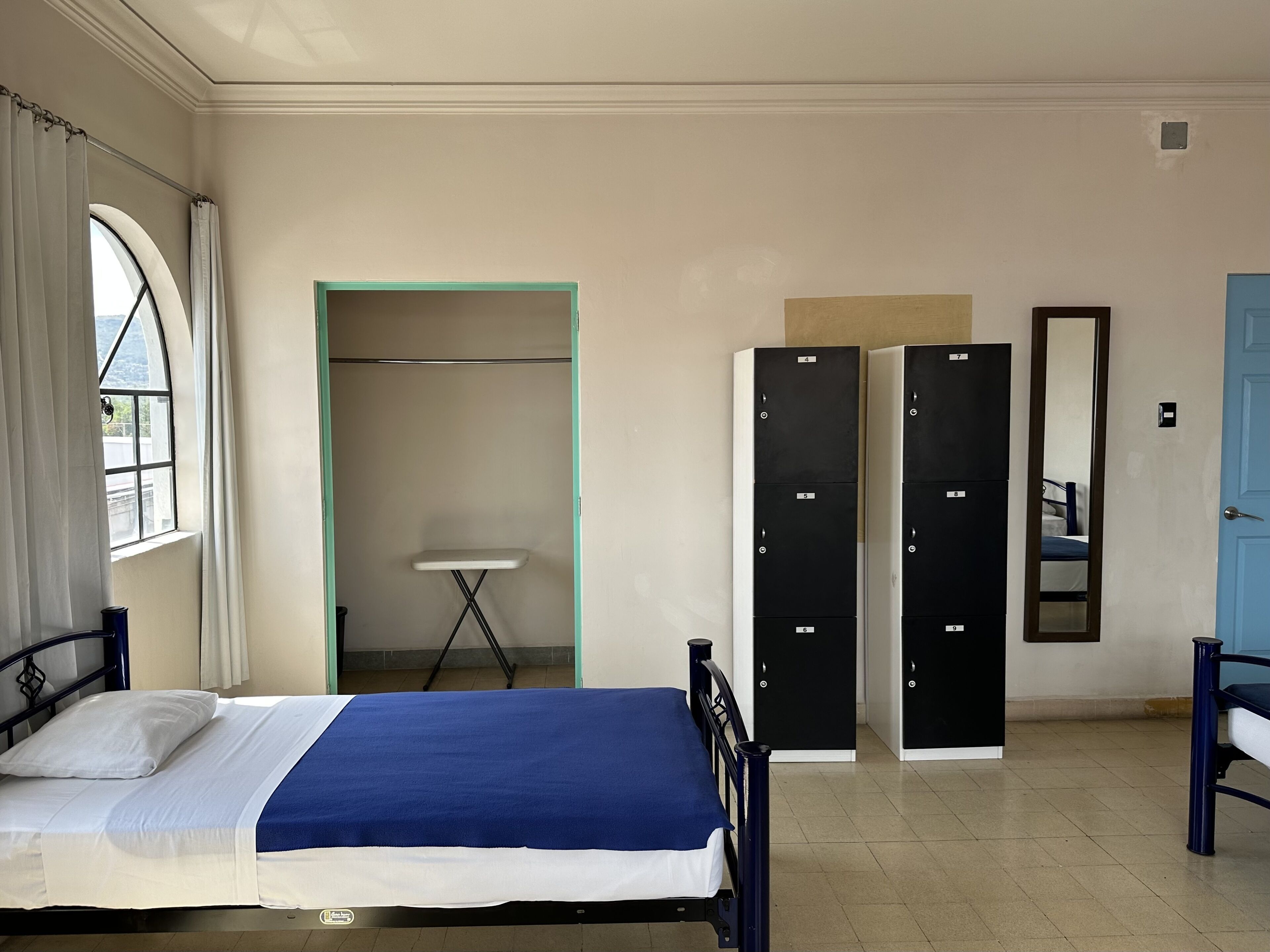 Ein Schlafzimmer mit Bett, Kleiderschrank, Spiegel und Fenster.