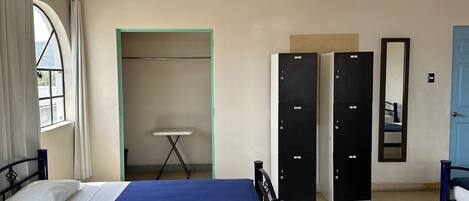 Ein Schlafzimmer mit Bett, Kleiderschrank, Spiegel und Fenster.