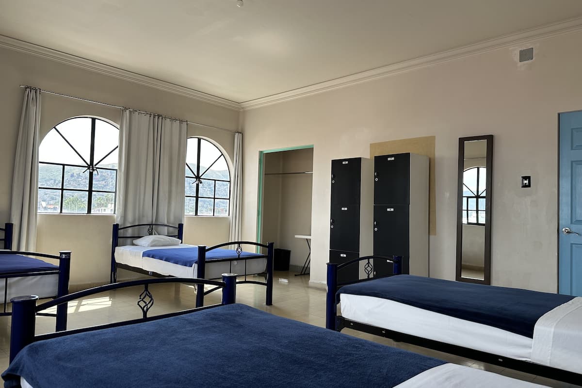 Une chambre d’hôtel avec deux lits, une grande fenêtre, une armoire et une porte.