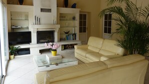 A living room with a fireplace, a sofa, a coffee table, and a bookshelf. - Locatlantique (Aytre)