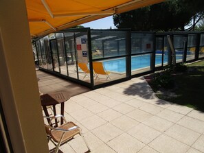 A covered outdoor area with a pool, glass enclosure, and seating. - Locatlantique (Aytre)