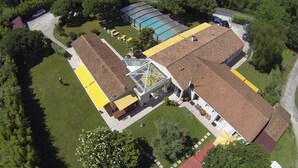An aerial view of a building with a large glass conservatory, a swimming pool, and a red-roofed section. - Locatlantique (Aytre)