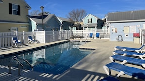 Une piscine avec des chaises longues et une clôture blanche.