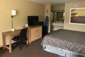 A hotel room with a bed, a desk with a computer, a chair, a TV, a mirror, and a painting on the wall. - Days Inn by Wyndham Lexington (Lexington)
