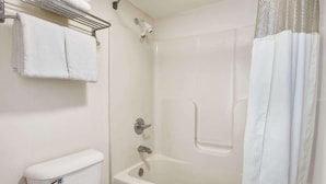 A bathroom with a white bathtub, a showerhead, a towel rack with folded towels, and a toilet. - Days Inn by Wyndham Lexington (Lexington)