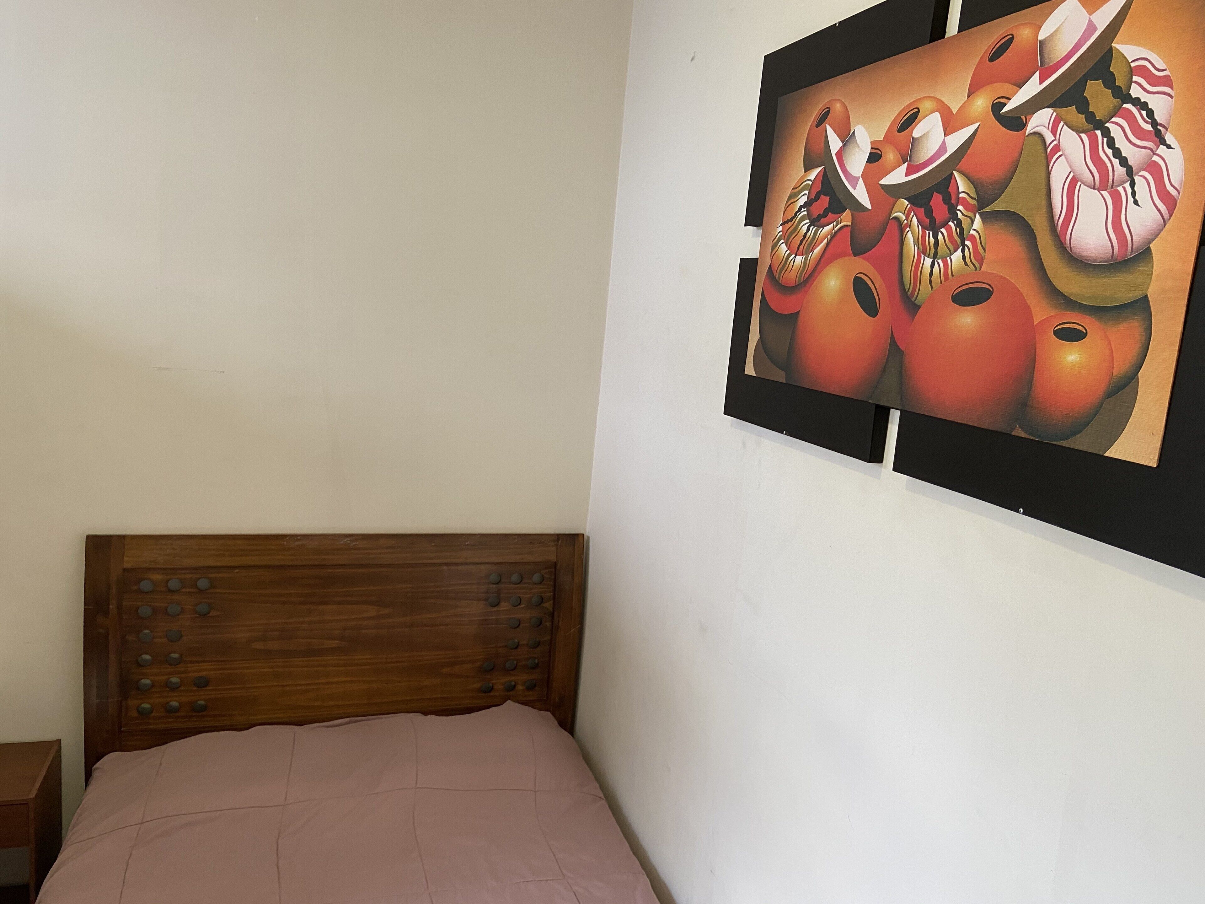 Un dormitorio con cabecera de madera y cama con colcha rosa.