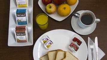 Un desayuno con tostadas, fruta, un vaso de jugo, una taza de café y varios productos de McColin.