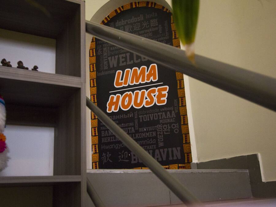 A sign with 'LIMA HOUSE' written on it, a metal railing, and a small dog with a colorful collar.