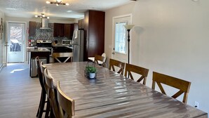 A spacious kitchen with dark wooden cabinets, stainless steel appliances, and a wooden dining table with chairs. - FREE Amenity Passes Spacious Sauna Large Deck Firepit (Lehman township)
