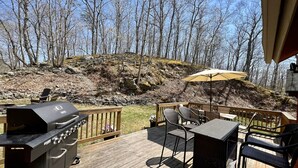 A deck with a grill, outdoor furniture, and a view of a wooded hillside. - FREE Amenity Passes Spacious Sauna Large Deck Firepit (Lehman township)