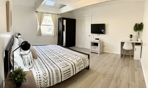 A bedroom with a large bed, a desk, a TV, and a wardrobe. - FREE Amenity Passes Spacious Sauna Large Deck Firepit (Lehman township)