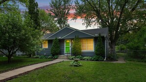 A single-story house with a green door, a small front porch, and a well-maintained lawn. - 10 BEDS in 4 BR! Quiet comforts in the city. (Minneapolis)