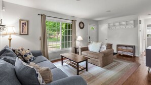 A living room with a sofa, two armchairs, a coffee table, a lamp, a clock, and a window with curtains. - 10 BEDS in 4 BR! Quiet comforts in the city. (Minneapolis)