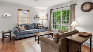 A living room with a sofa, a coffee table, a lamp, and a window with curtains. - 10 BEDS in 4 BR! Quiet comforts in the city. (Minneapolis)