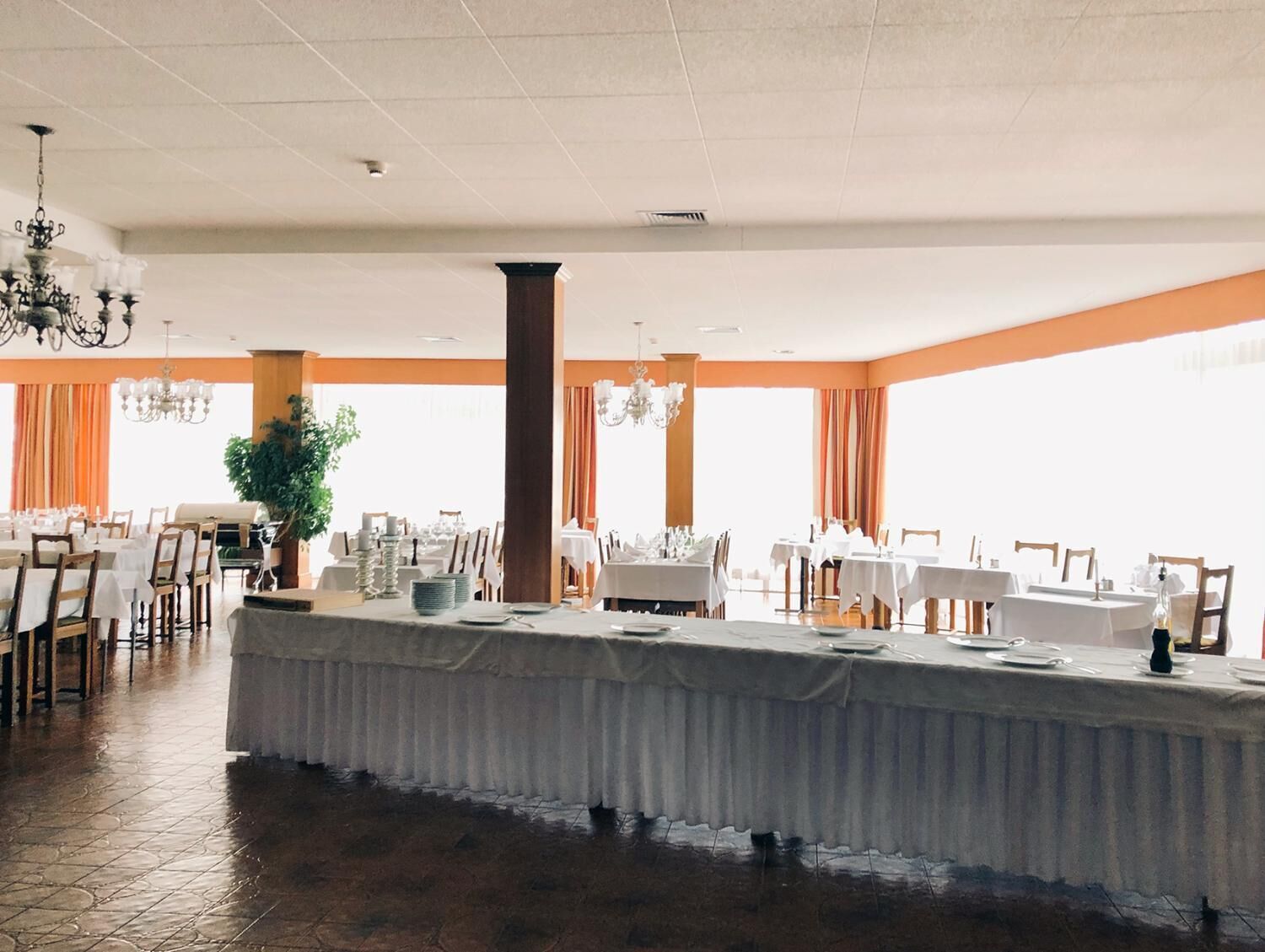 Un amplio salón de banquetes con techos altos, grandes ventanales y una zona de bar central.