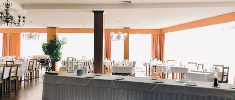 Un amplio salón de banquetes con techos altos, grandes ventanales y una zona de bar central.