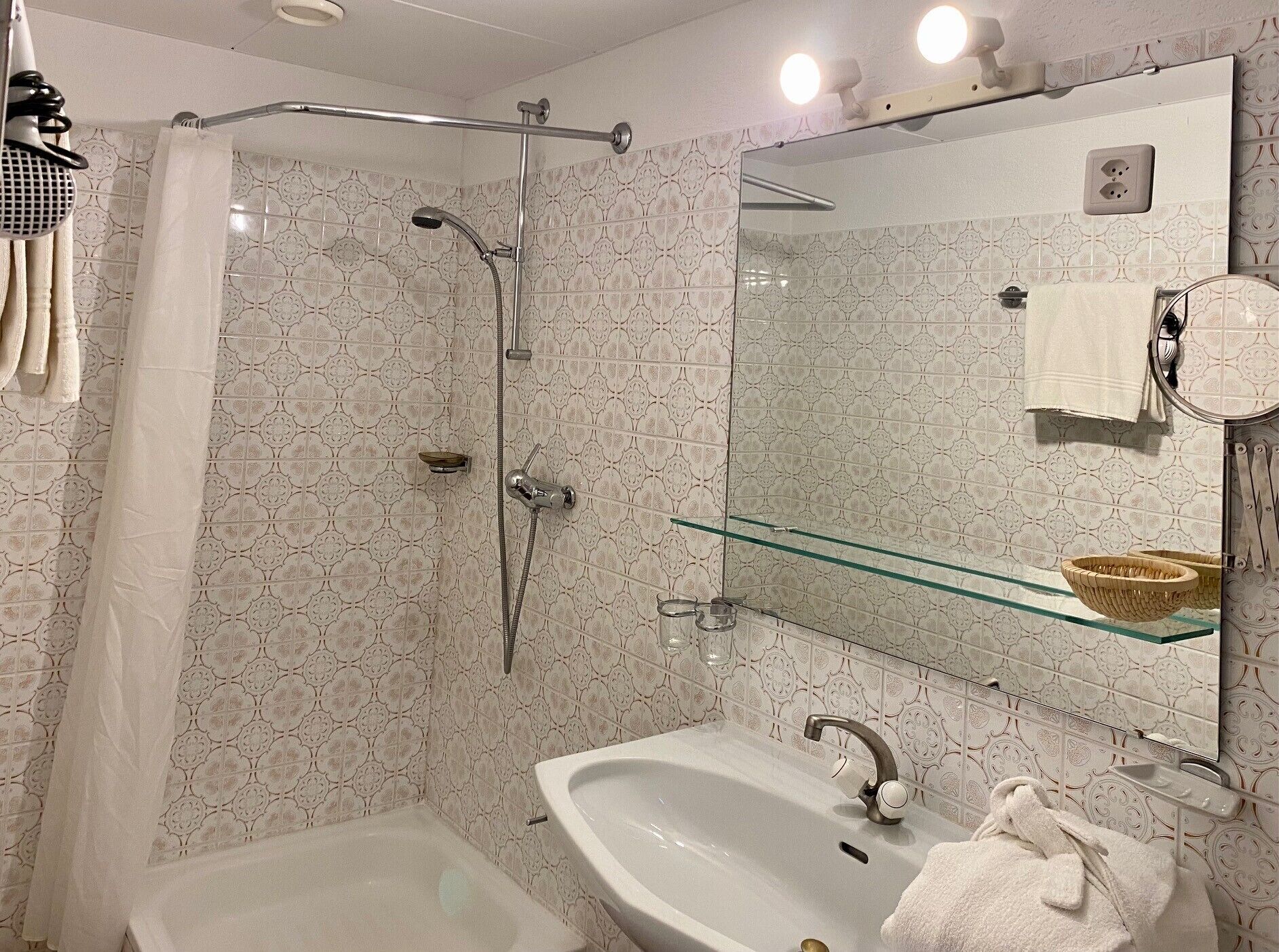 Casa de banho com chuveiro, lavatório e espelho.
