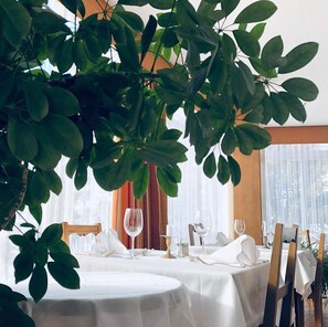 A dining area with a table set for two, surrounded by large green plants. - Hotel Regina Terme (Leukerbad)
