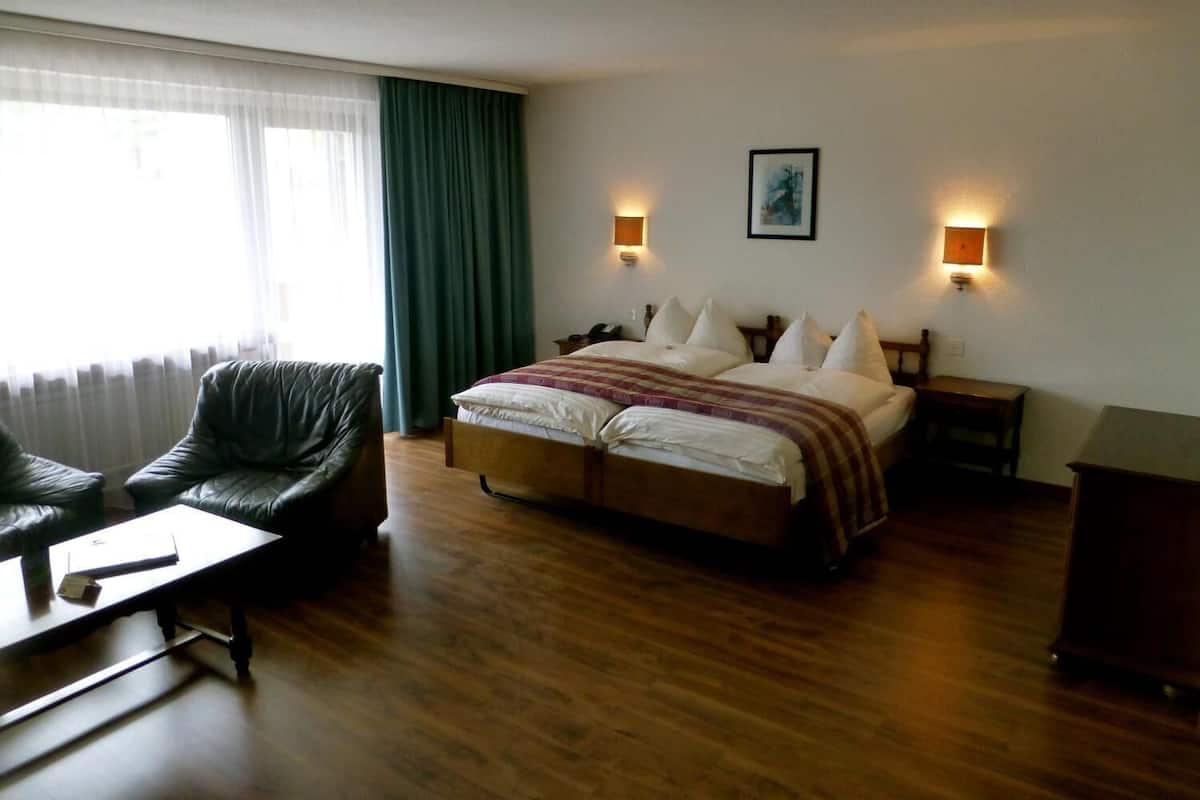 Una habitación de hotel con una cama grande, dos mesitas de noche, una silla y un escritorio.