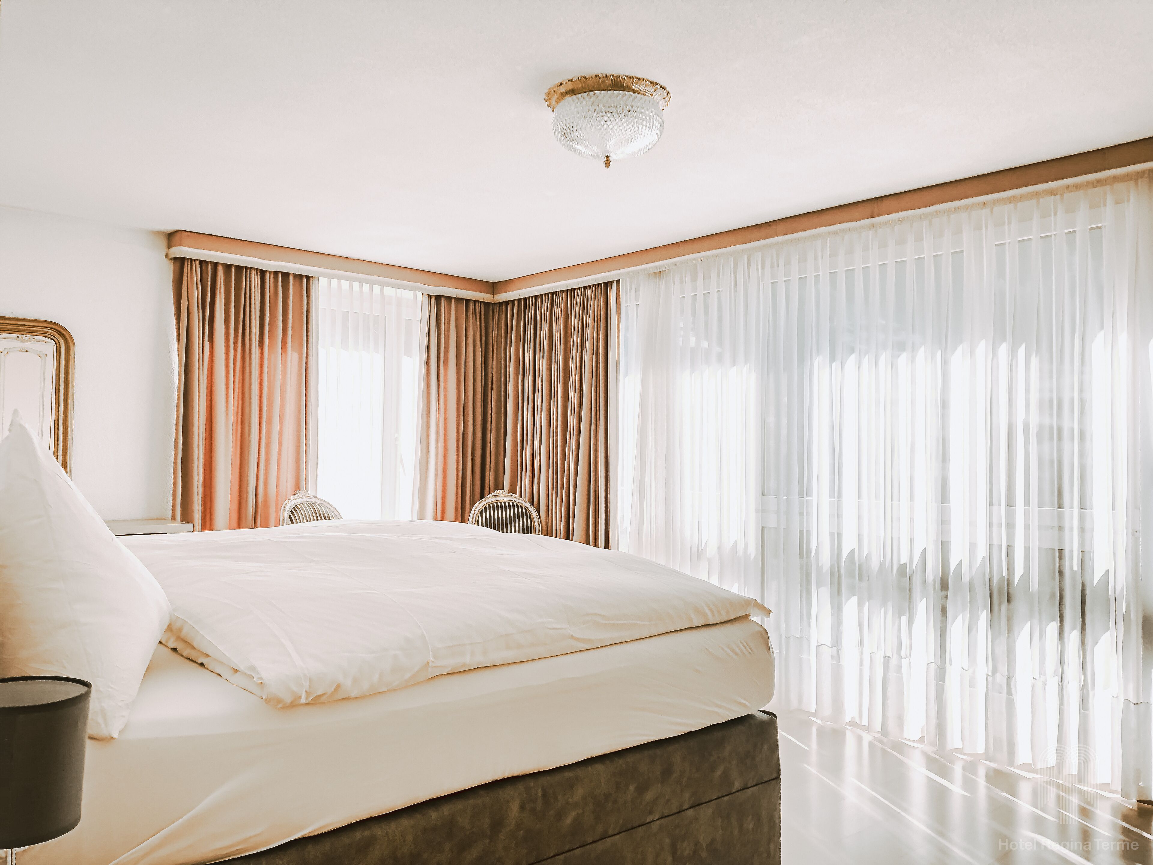 A modern hotel room with a large bed, a desk, and a chair.