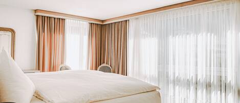 A modern hotel room with a large bed, a desk, and a chair.