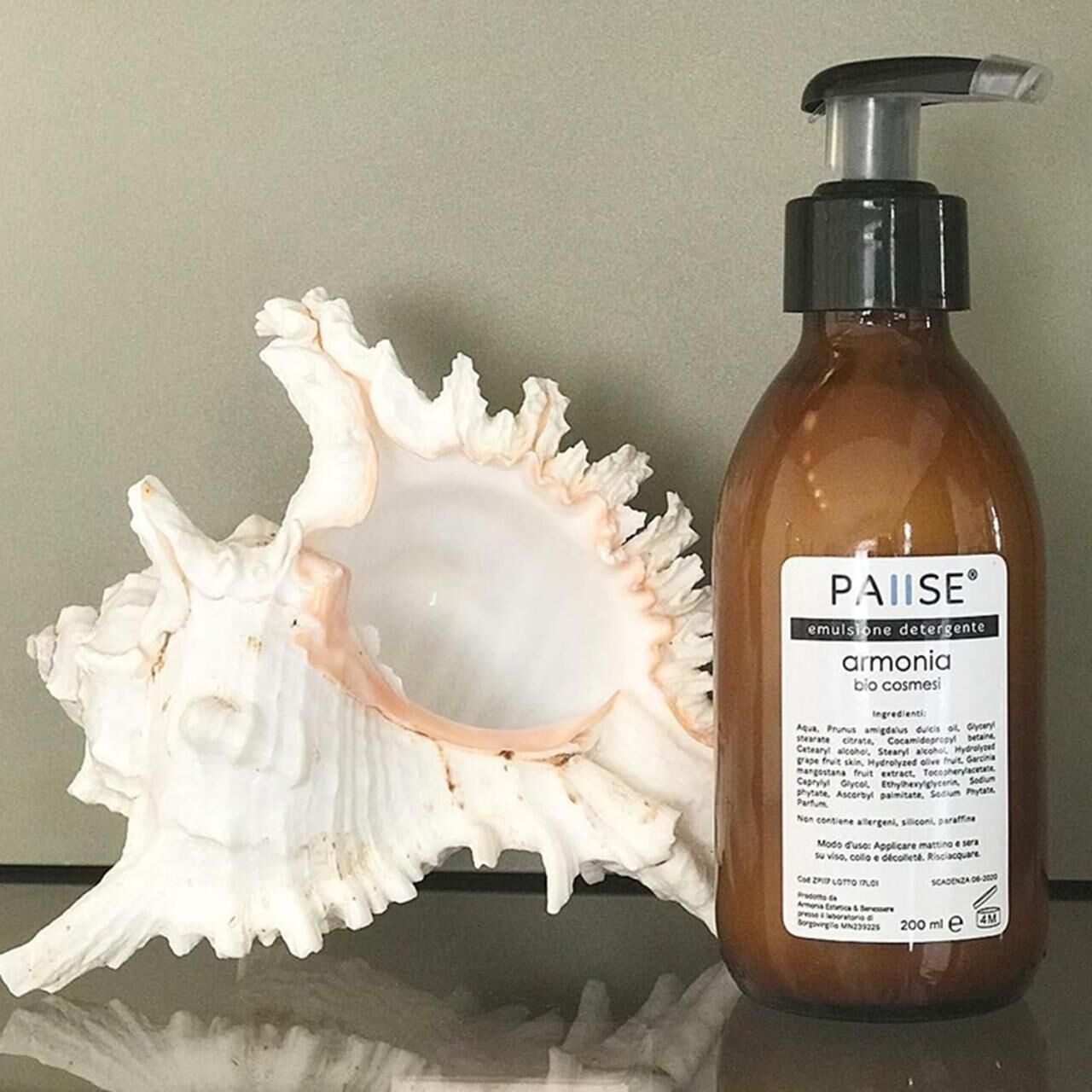 Una botella de detergente emulsionante PAIISE junto a una concha marina.