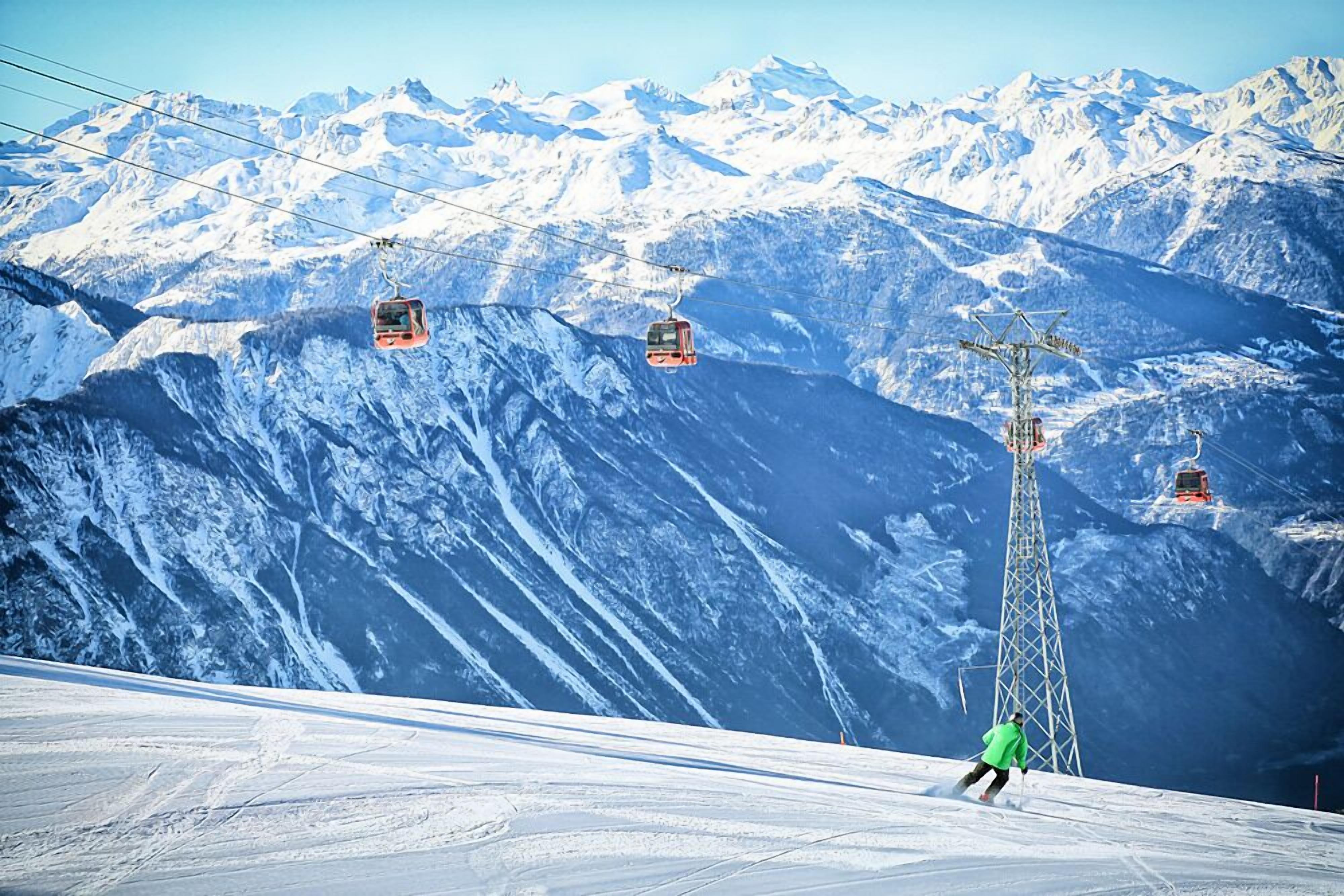 A ski lift with a person skiing down the slope.
