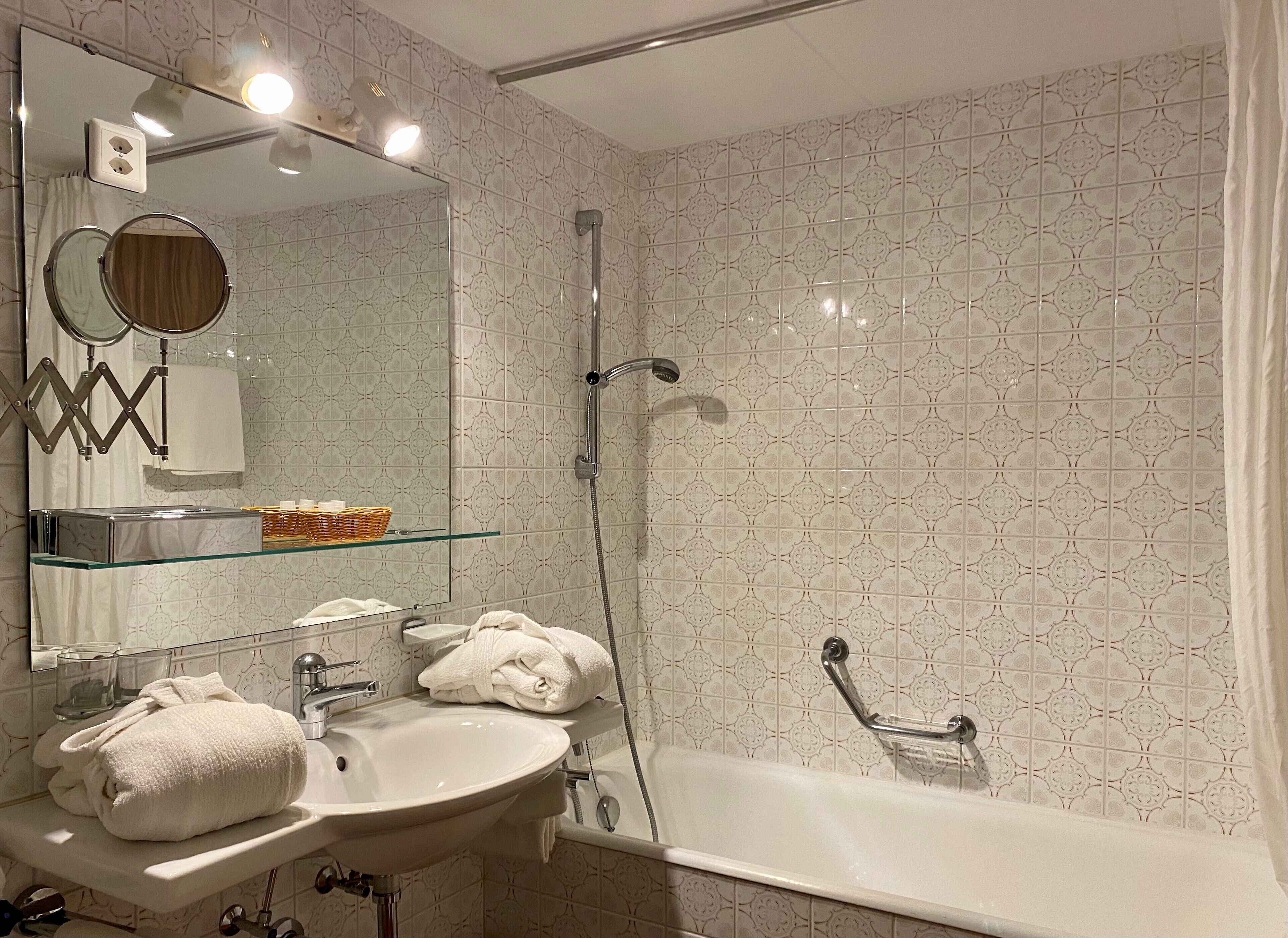 A modern bathroom with a glass shelf, a sink, a mirror, a shower, and a bathtub.