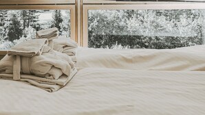 Un dormitorio con un ventanal grande, suelo de madera y una silla.